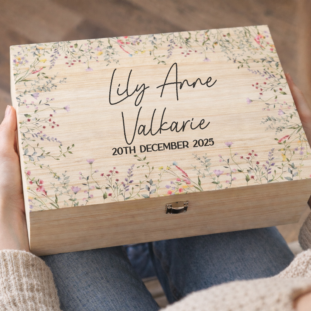 Person holding a wooden box with floral design and engraved text